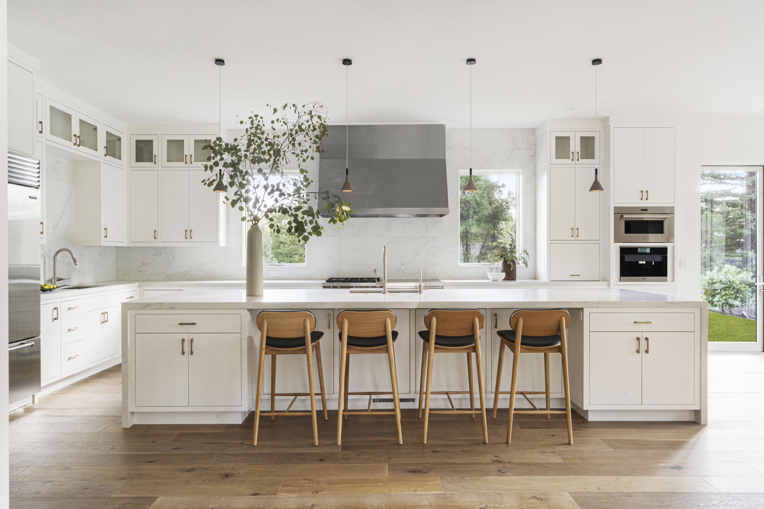 Bright white kitchen with white island and wooden stools